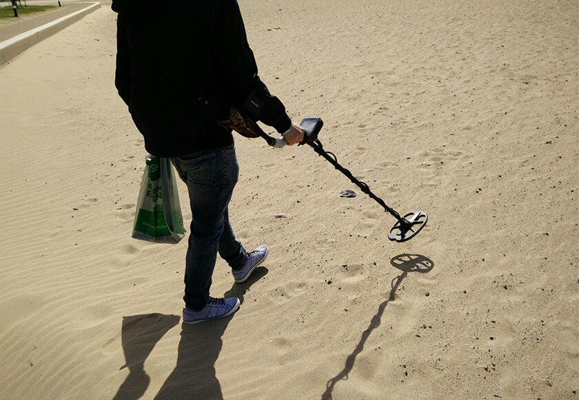 Man with Metal Detector on Sand